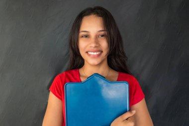 Gülümseyen ve elinde mavi bir tahta tutan neşeli genç bir kadın.