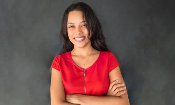 Happy hispanic woman smiling on grey wall