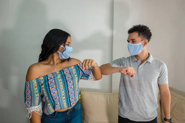 Maskeli çift dirsekleriyle birbirlerine el sallıyor. Sosyal uzaklık kavramı