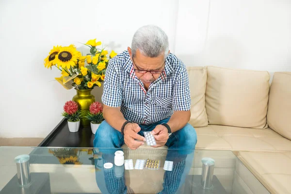 A grown man with gray hair checking medication in his living room at home.