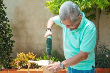 Yaşlı adam ahşap bir kutu yapıyor.