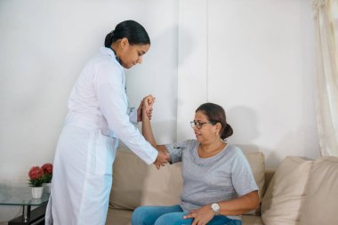 Nörolojik muayene sırasında nörolog tarafından yapılan triseps derin tendon refleksi testi. Nöroloji uzmanı elinde nörolojik bir çekiç tutuyor ve el uzatma kaslarıyla refleks eğrisinin durumunu kontrol ediyor.