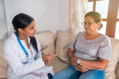 Latin Doktor kadın hastasına teşhisi açıklıyor.