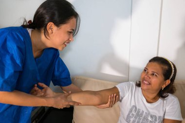 Fizyoterapideki hasta terapistiyle fizik tedavi egzersizleri yapıyor.