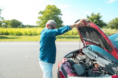 Maskeli bir adam seyahat ederken arabasını bozuyor.