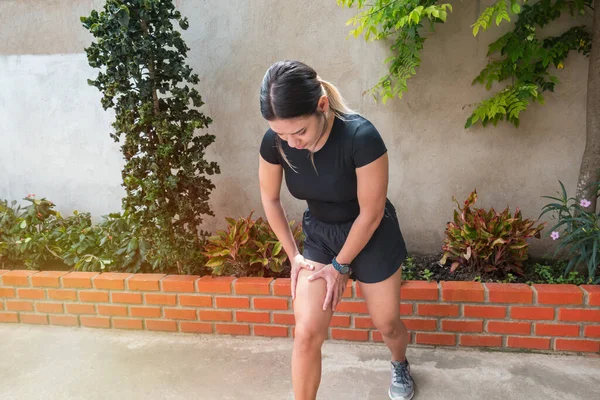 Muscle injury. Runner woman with sprain thigh muscle. Athlete in sports shorts clutching his thigh muscles after pulling or straining them while jogging on the park wearing running shoes.