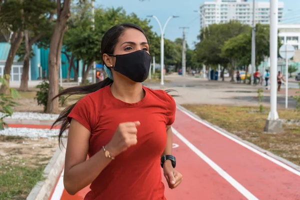 Hispanic woman with a mask running through the park. Healthy Lifestyle