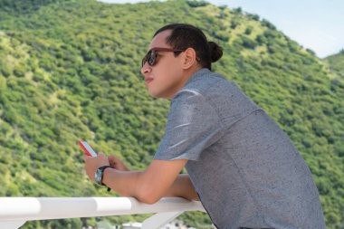 Güneş gözlüklü yakışıklı, genç bir İspanyol girişimci akıllı bir telefon tutar, kafasını çevirir ve dışarıda dururken düşünür.