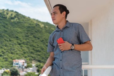 Balkonda tişörtlü bir İspanyol duruyor.