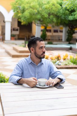 Düşünceli iş adamı dışarıda kahve içiyor ve başka yere bakıyor.