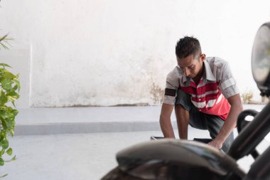 Erkek tamirci garajda motosiklet tamir ediyor ve bakım yapıyor.