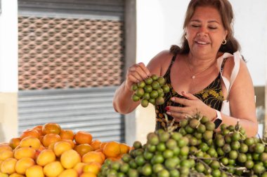 Yerel bir marketteki meyve tezgahından taze ürün seçen mutlu kadın.