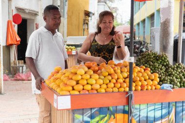 Alışverişçiler açık hava pazarındaki bir satıcıdan taze ürün seçiyorlar.