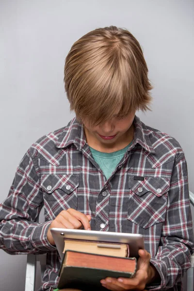 Boy holds books and tablet, focus on book and hand