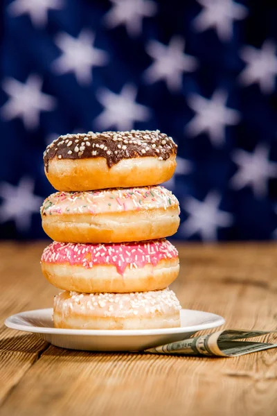 Pile of donuts and money on the table over american flag background