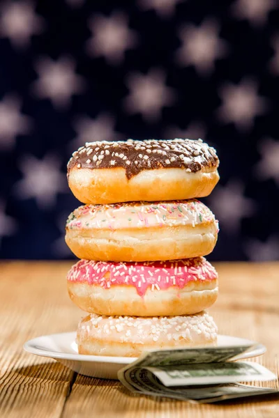 Stack of donuts and money on the table over american flag background