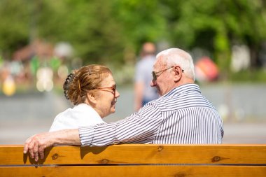 Şehir parkında bir bankta oturan rahatlatıcı sunlglasses giyen yaşlı çift