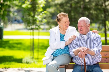 Neşeli yaşlı çift şehir parkında iyi vakit geçiriyor, yürüyor, gülüyor ve güneşli bir günün tadını çıkarıyor