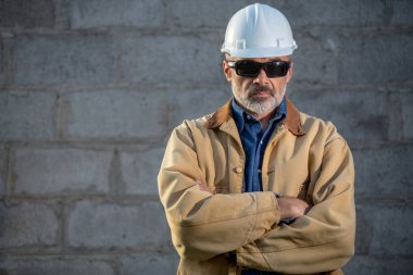 beton duvar arka plan üzerinde sert şapkalı inşaat işçisi