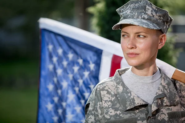 Beautiful american soldier in uniform standing in front of american flag