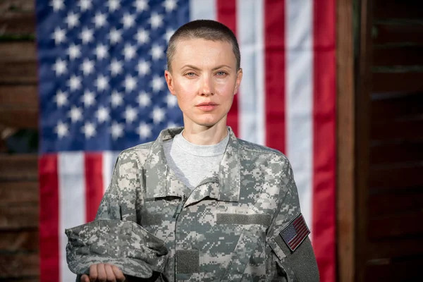 美丽的美国士兵站在美国国旗前 图库图片