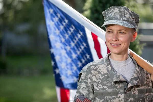 美丽的美国士兵站在美国国旗前 图库照片