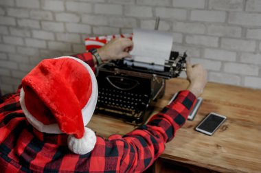 Modern Noel Baba klasik daktilo ve daktilo ile Mutlu Noeller yazıyor. Noel Baba bayramı kutlamaya hazırlanıyor.