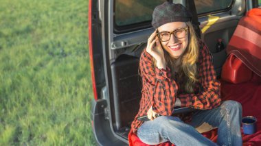 Dizüstü bilgisayarda çalışan mutlu genç bir kadın, video görüşmesi yapıyor ve uzun bir günün ardından araba kullandıktan sonra dinleniyor.