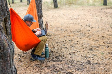 Neşeli bir adamın portresi, bilgisayarında video kaydı olan bir yerden bilgisayarda çalışıyor.