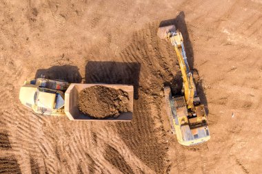 Kazıcı toprağı eklemeli nakliye kamyonuna yüklüyor.