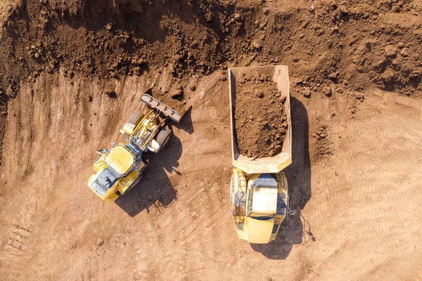 Excavadora cargando tierra sobre un camión de transporte articulado — Foto de Stock