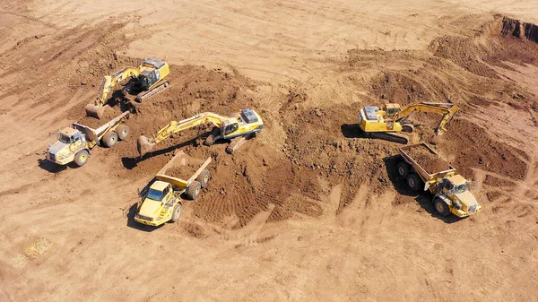 Excavadora cargando tierra sobre un camión de transporte articulado —  Fotos de Stock