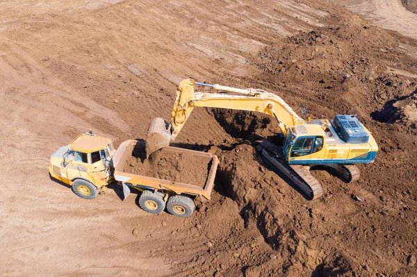 Excavadora cargando tierra sobre un camión de transporte articulado — Foto de Stock