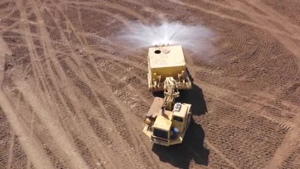 Articulated Water Truck spraying water on a large Excavation site. — Stock Video
