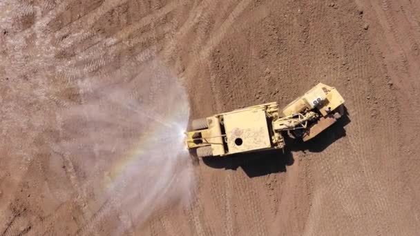 Articulated Water Truck spraying water on a large Excavation site. — Stock Video