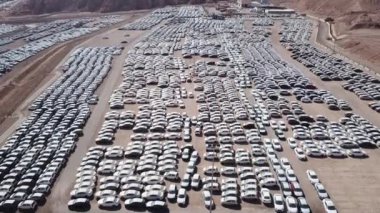 Bekleme platformunda park etmiş koruyucu beyaz çarşaflarla kaplı yeni arabalar..