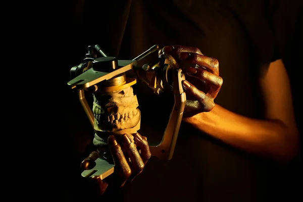 Две золотые руки с зубным инструментом на черном фоне — стоковое фото