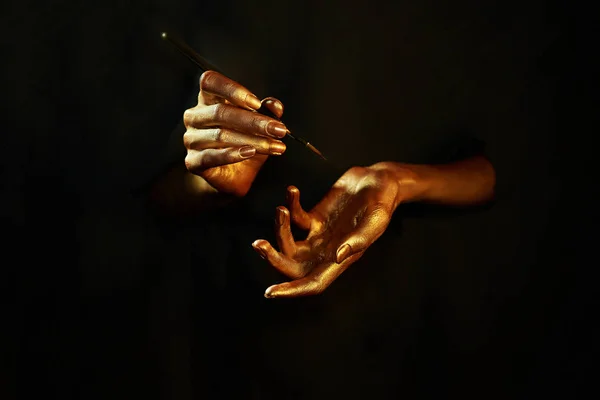 Oro manos witn cepillo aislado sobre fondo negro — Foto de Stock