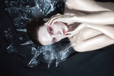 girl with whitened skin and red make-up in ice on a black background clipart