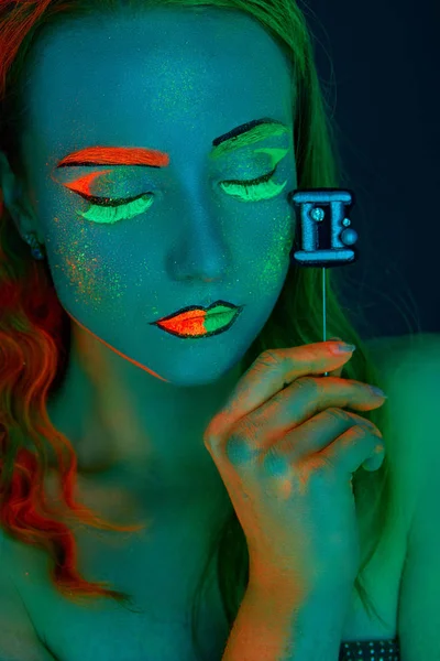 Mädchen im Bild des Tierkreiszeichens Zwillinge im UV-Licht mit kreativem Make-up — Stockfoto