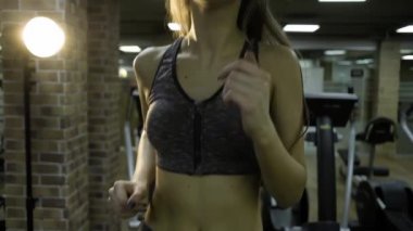 Güzel kız siyah bir arka plan üzerinde spor salonunda bir simülatör üzerinde meşgul