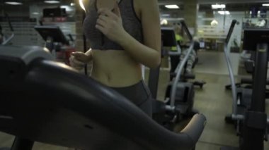 Güzel kız siyah bir arka plan üzerinde spor salonunda bir simülatör üzerinde meşgul