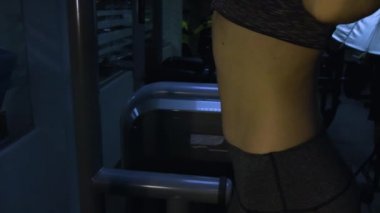 Güzel kız siyah bir arka plan üzerinde spor salonunda bir simülatör üzerinde meşgul