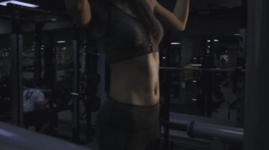Güzel kız siyah bir arka plan üzerinde spor salonunda bir simülatör üzerinde meşgul