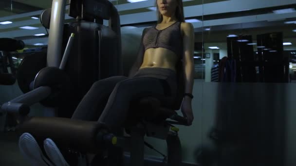 Menina bonita envolvida em um simulador no ginásio em um fundo preto — Vídeo de Stock