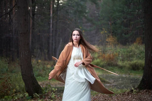 Дівчина в білій сукні і коричневе пальто в осінньому лісі — стокове фото