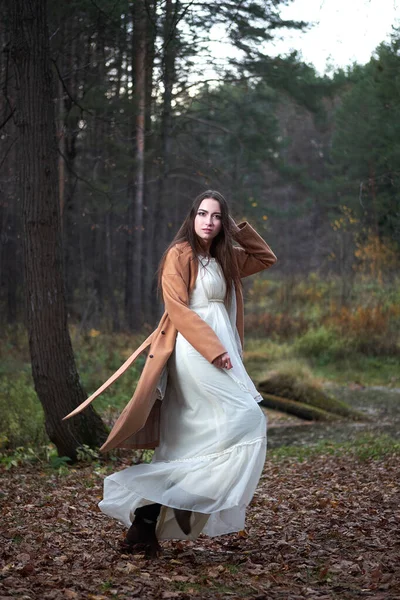 Дівчина в білій сукні і коричневе пальто в осінньому лісі — стокове фото