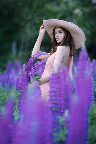 Blond leende ung kvinna som håller en lupin bukett på naturen bakgrund. Begreppet skönhet och romantik. — Stockfoto