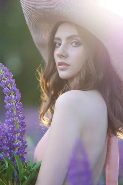 Blond glimlachende jonge vrouw met een lupine boeket op de achtergrond van de natuur. Het concept van schoonheid en romantiek. — Stockfoto