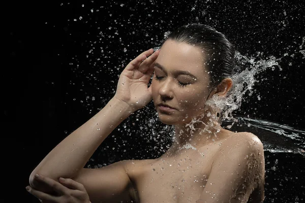 Mulher jovem com pele limpa e respingo de água. Retrato de mulher com gotas de água ao redor de seu rosto preto e branco — Fotografia de Stock